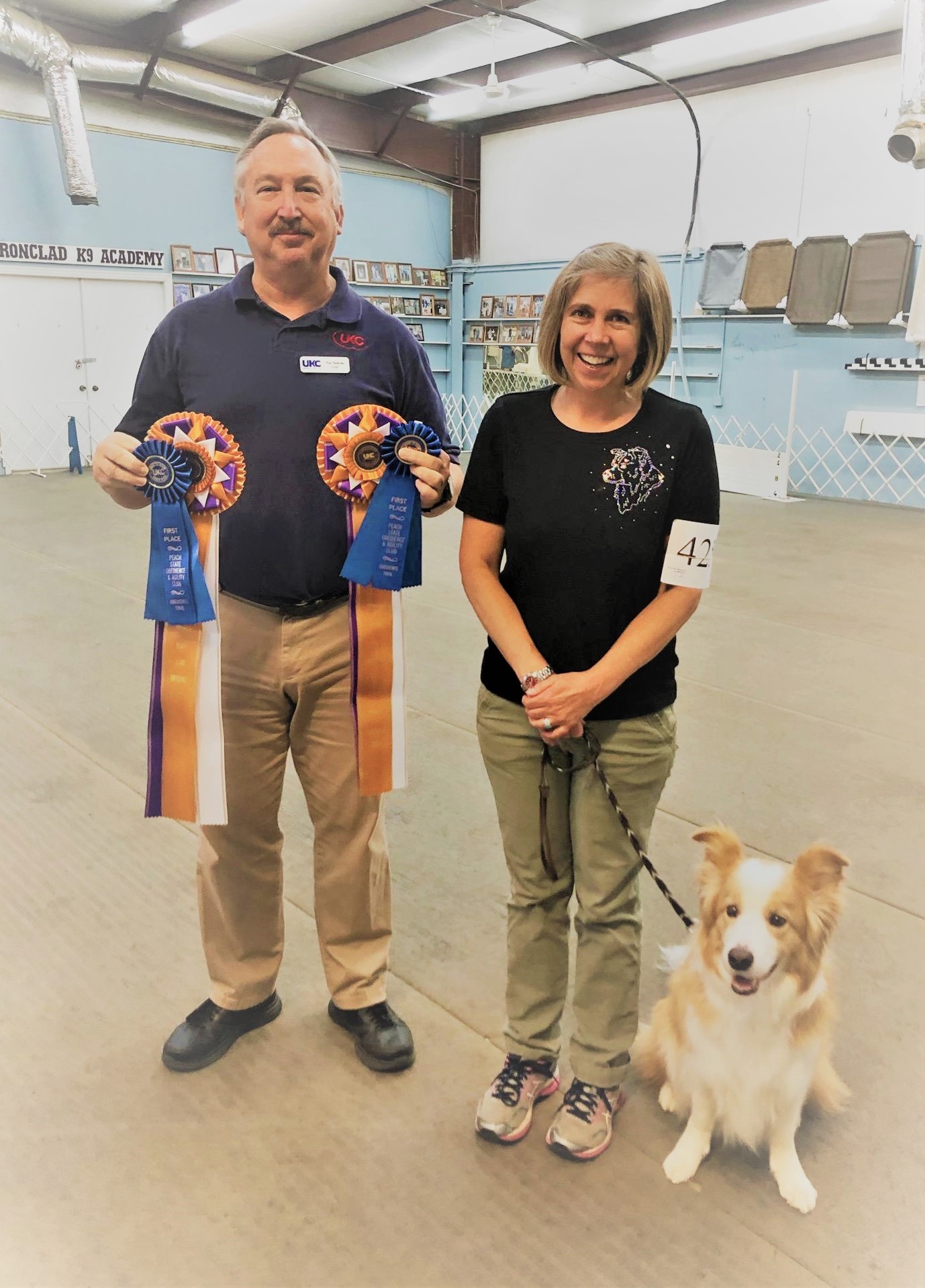Dog With Trainer And Owners Holding Medals